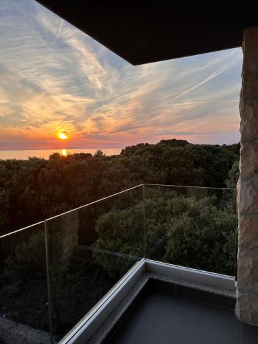 einen Blick auf den Sonnenuntergang vom Balkon eines Hauses in der Unterkunft Lili Rose Mandre Luxury Apartments in Mandre