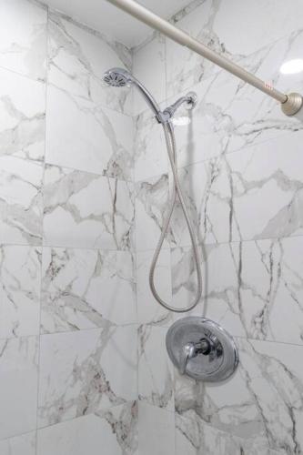 a bathroom with a shower with white marble walls at New DT Alhambra Family Vacation Home with King Bed in Alhambra