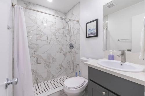 a white bathroom with a shower and a toilet and a sink at New DT Alhambra Family Vacation Home with King Bed in Alhambra