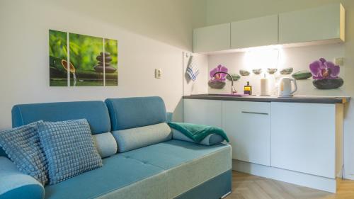 a living room with a blue couch and a kitchen at Apartament Ski Sudety Karpacz in Karpacz