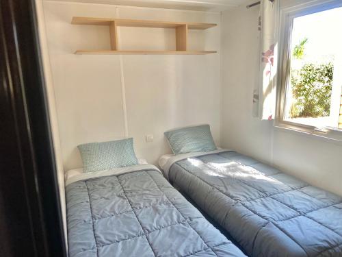 deux lits dans une petite pièce avec une fenêtre dans l'établissement Tiny House, Mobilhome 6 personnes au Port de Vendres plage, à Vendres