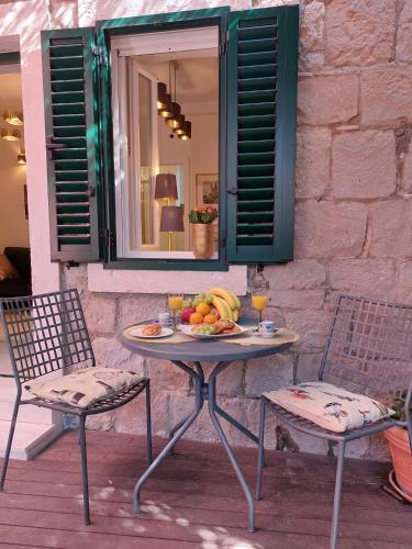 a table with a plate of fruit and two chairs at Split Old Town Oasis in Split