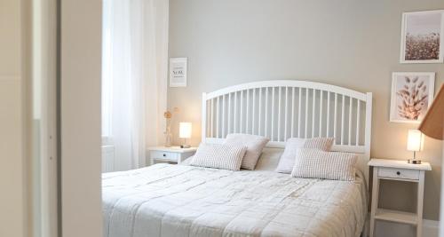 een slaapkamer met een wit bed en 2 nachtkastjes bij gemütliches Ferienhaus hinterm Deich in Friedrichskoog