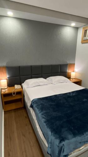 a bedroom with a bed with a blue blanket on it at Flat confortável com recepção 24h e vaga de garagem in São Paulo