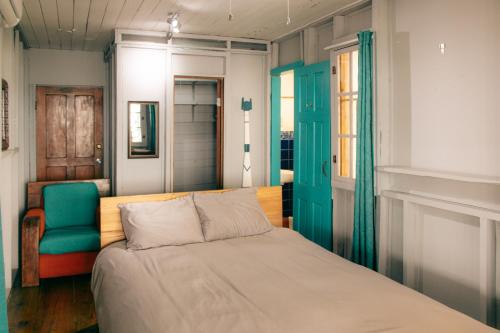 1 dormitorio con 1 cama y 1 silla azul en Saigon Bay Bed & Breakfast en Bocas del Toro