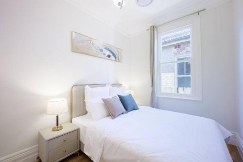 Un dormitorio blanco con una cama blanca y una ventana en Cosy Federation Apartment Kirribilli 2 Bedroom #1, en Sídney