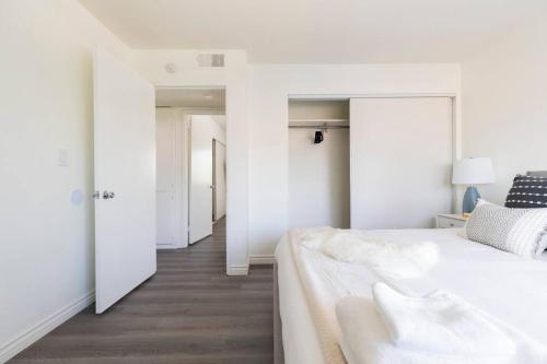 a white bedroom with a large bed and a hallway at Modern 2BR Condo with King Bed & Balcony near LA in Alhambra