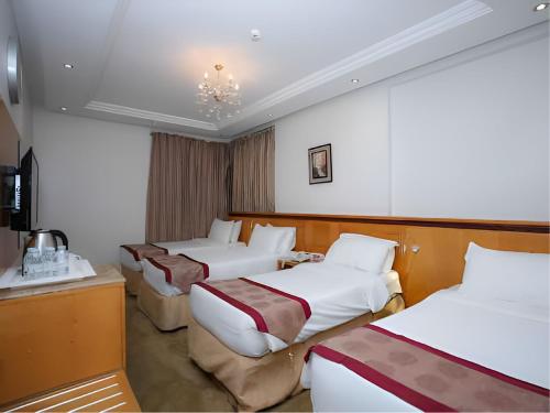 a hotel room with three beds and a television at Nasamaat Ajyad Hotel in Mecca