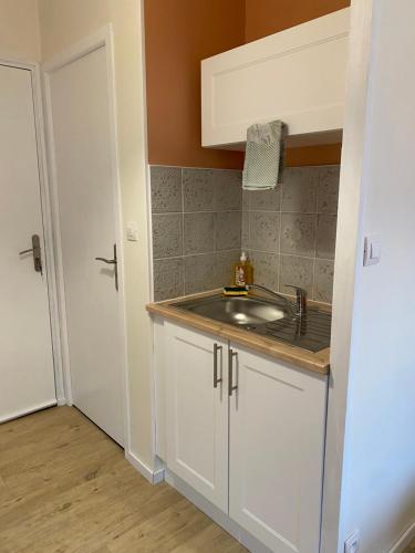 uma cozinha com um lavatório e um armário branco em Au réconfort de Mers Draps et Serviettes fournies Appartement 12 em Mers-les-Bains