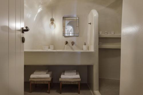 baño con lavabo, espejo y 2 taburetes en Blue Art Caves, en Oia