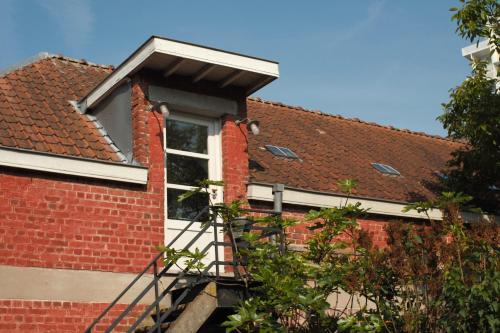 a brick house with a window and a ladder at De Hamrokerij in Kortrijk
