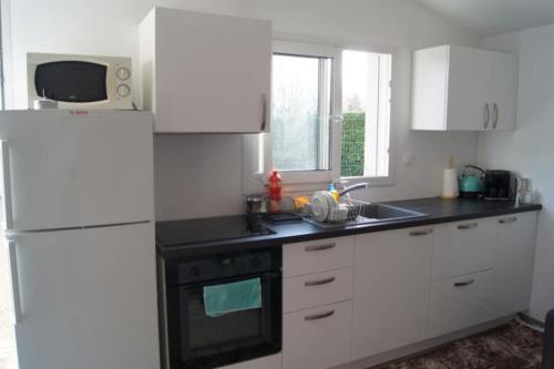 La cuisine est équipée de placards blancs et d'un four avec plaques de cuisson noires. dans l'établissement Maison au calme, parking privée, à Saint-Rémy