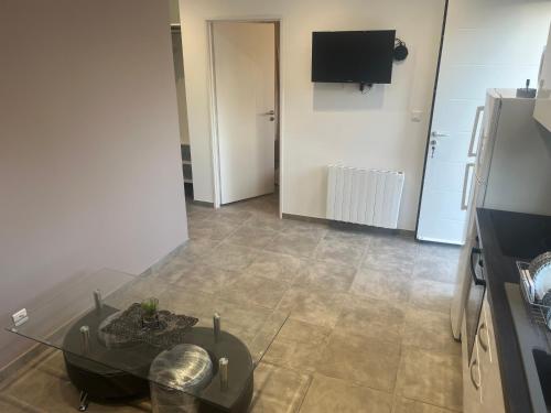 un salon avec une table en verre et une télévision dans l'établissement Maison au calme, parking privée, à Saint-Rémy