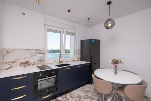 una cucina con frigorifero nero e tavolo bianco di Lux Top Location Apartment Bridge a Zara (Zadar)