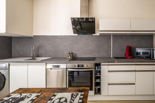 une cuisine avec des armoires blanches et un four à plaques de cuisson dans l'établissement L'appart ciné, T2 Centre ville Narbonne, à Narbonne