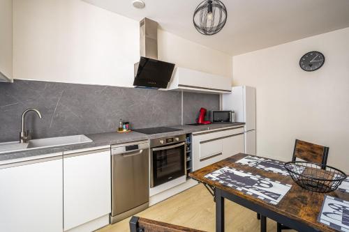 une cuisine avec des armoires blanches et une table en bois dans l'établissement L'appart ciné, T2 Centre ville Narbonne, à Narbonne