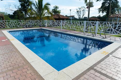 a swimming pool with blue water in front of a fence at Colina del Sol Hotel Hacienda in Quimbaya