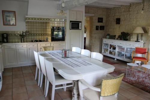 eine Küche mit einem weißen Tisch und weißen Stühlen in der Unterkunft Chambres d'hôtes du Noisillet in Cinais