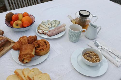 une table blanche surmontée d'assiettes de pâtisseries et de fruits dans l'établissement Le Clos du Noisillet, à Cinais