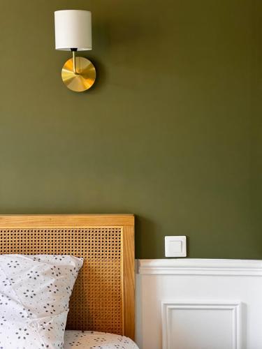 a bedroom with a green wall with a bed and a lamp at Appartement Richard Merrill, en plein centre, 4 pers in Sainte-Mère-Église