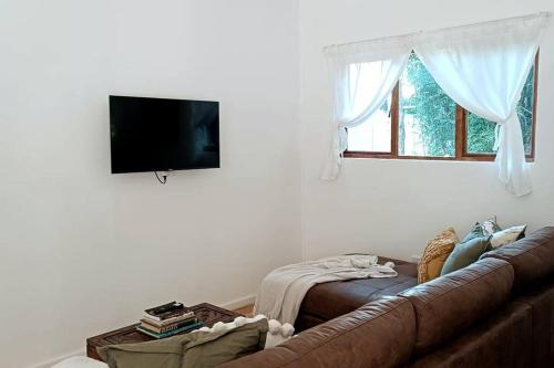 a living room with a brown couch and a window at Entire cottage in Stormsriver in Stormsrivier