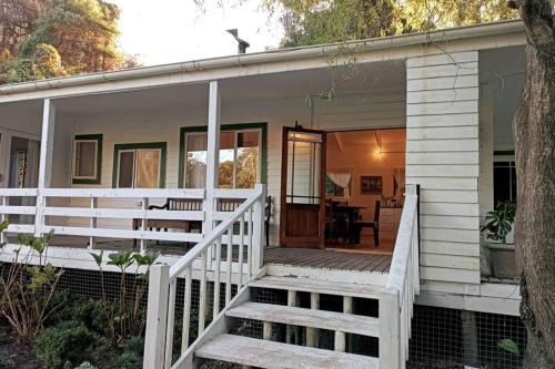 a white house with a porch and a staircase at Entire cottage in Stormsriver in Stormsrivier