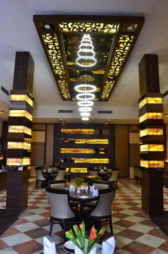 a restaurant with tables and chairs and a chandelier at Hotel Abhinandan in Mathura