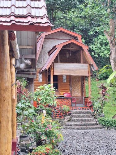 a small wooden house with stairs in a garden at Lucky Bamboo'Bungalows-Resto and Orangutan Jungle Trekking Tours in Bukit Lawang