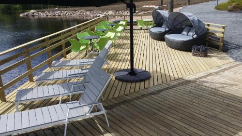 a wooden deck with chairs and tables and an umbrella at Hotelli Viikinhovi in Keuruu