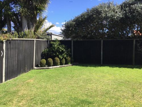uma cerca com um quintal com relva e arbustos em 驿站 em Auckland