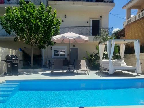 a pool with an umbrella and chairs and a house at Amare suite in Perivólia