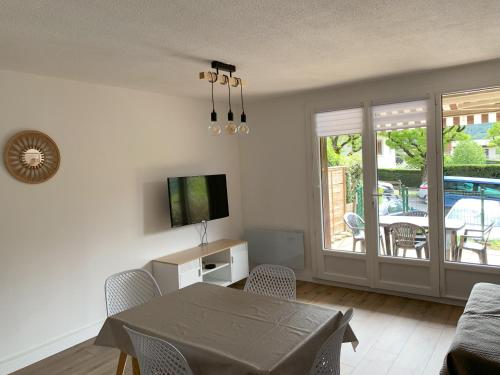 ein Wohnzimmer mit einem Tisch und einem TV in der Unterkunft Agréable T2 en rez de jardin à 2 pas du plan d'eau in Embrun