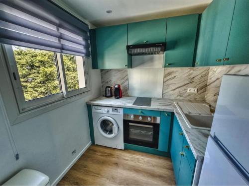une cuisine avec des armoires vertes et une machine à laver dans l'établissement Studio Picaud proche front mer, à Cannes