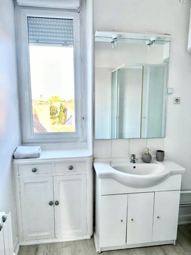 a white bathroom with a sink and a window at Appartement moderne in Vierzon