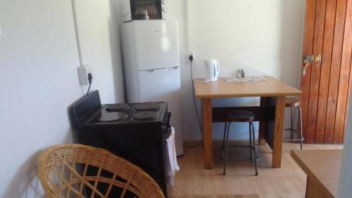 una cucina con piano cottura, tavolo e frigorifero di Megs Accommodation a Kamieskroon