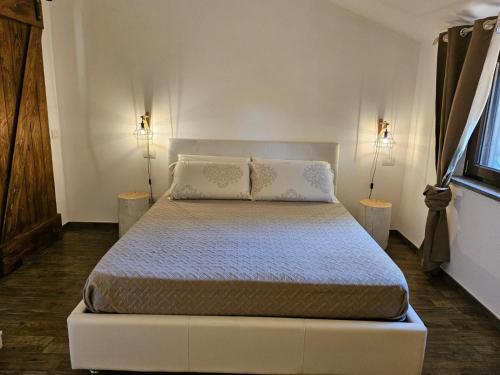 a white bed in a room with two lamps at Casale Valle Cardinale in Valmontone