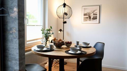 a dining room table with chairs and a lamp at Modernes Ferienhaus im Eidertal in Delve