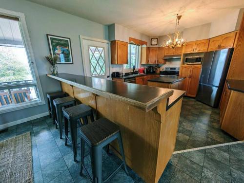 Exclusive Waterfront Cottage في Combermere: مطبخ مع بار خشبي كبير مع الكراسي