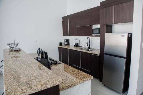 a kitchen with a stainless steel refrigerator and brown cabinets at Casa Villa Sol in Cuatrociénegas de Carranza