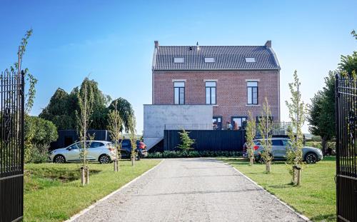 a brick house with cars parked in front of a driveway at Het Maashuis in Maasmechelen