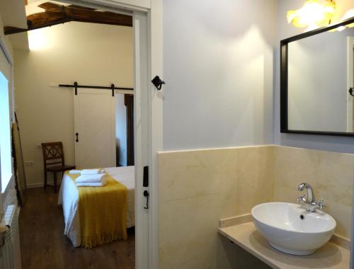 a bathroom with a sink and a mirror and a bed at Apartamentos Minas de Silvarosa in Viveiro