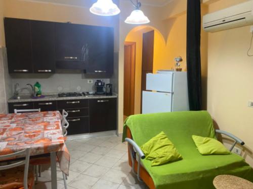 cocina con mesa y sofá verde en una habitación en Apartement Mimosa, en Scalea