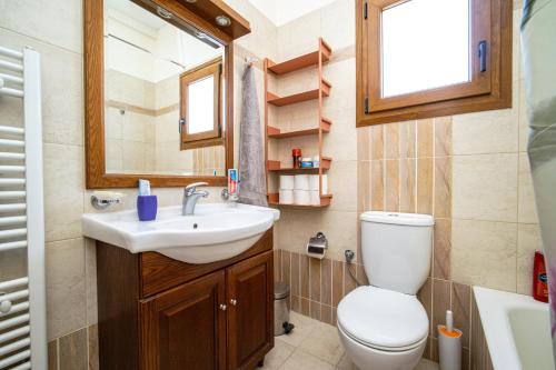 bagno con servizi igienici, lavandino e specchio di Villa Evans a Kokkónion