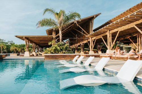 a pool with white lounge chairs in a resort at Villa Ocean Pearl Venao in Playa Venao