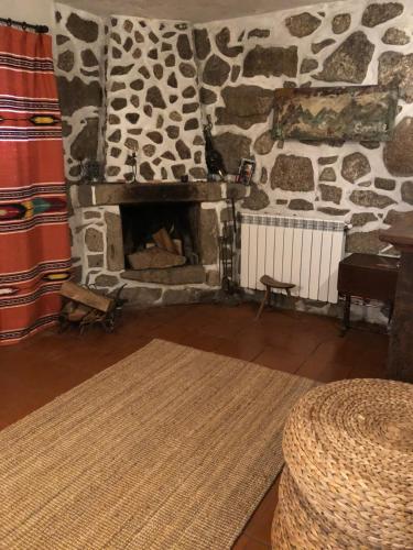 a living room with a stone fireplace and a rug at Chalés na Montanha - casa do lado - Serra da Estrela in Manteigas