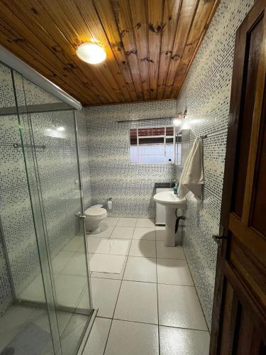 a bathroom with a toilet and a glass shower at Casa Recanto 3 in Campos do Jordão