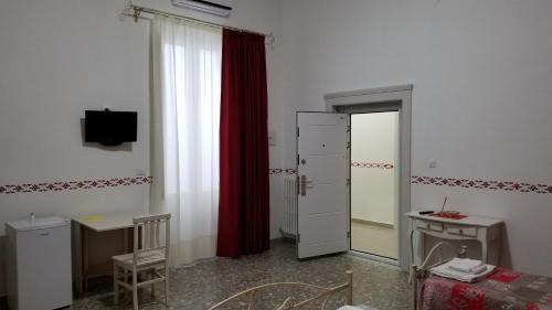 um quarto com uma janela, uma cortina vermelha e uma porta em B&B da Mino em Grottaglie
