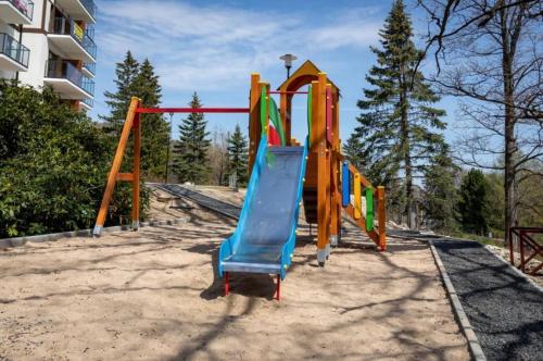 a playground with a slide in a park at Apartament Silence Green Park - Strefa SPA in Szklarska Poręba