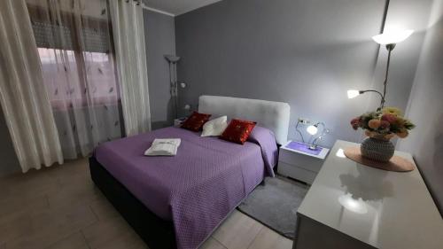 ein Schlafzimmer mit einem lila Bett und einem Tisch in der Unterkunft Da Daniela in Castiglion Fiorentino