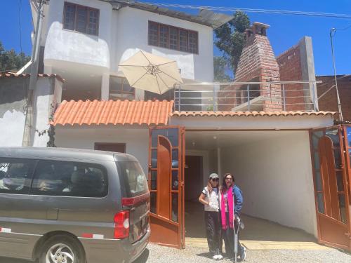 deux femmes debout devant une maison dans l'établissement Casa Hospedaje “YURAQ WASI”, à Huaraz
